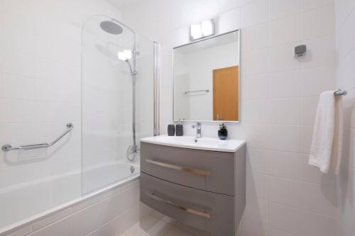 een witte badkamer met een wastafel en een spiegel bij Sarah's Apartment by GALMI in Caniço