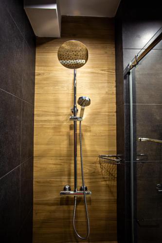 a shower in a bathroom with a wooden wall at New Gudauri Luxury Studio in Gudauri