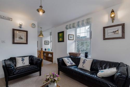 una sala de estar con un sofá de cuero negro y sillas en Jessamine: Restored fisherman's cottage close to Looe's harbour, en Looe