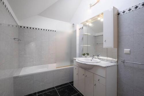 a white bathroom with a sink and a tub and a mirror at Villa Sol da Candelária by GALMI in Ribeira Brava