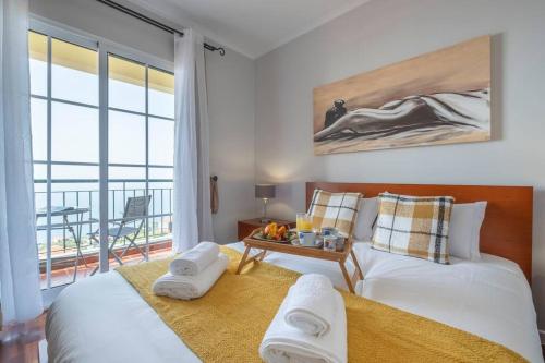 a bedroom with two beds and a table and a balcony at Villa Sol da Candelária by GALMI in Ribeira Brava