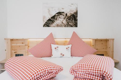 a bedroom with a bed with red and white pillows at Nedererhof - Zimmer Edelweiß mit Gemeinschaftsküche in Schmirn