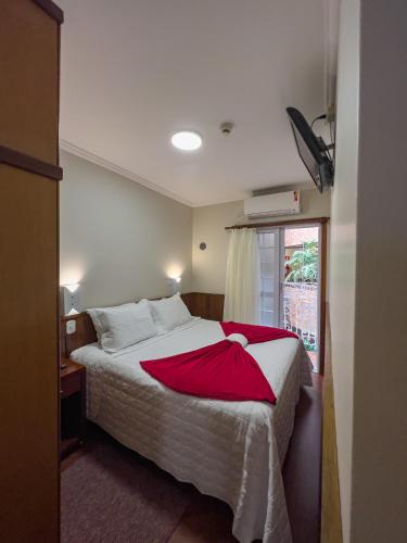 a bedroom with a bed with a red blanket on it at Hotel Palazzo Reale in Campos do Jordão