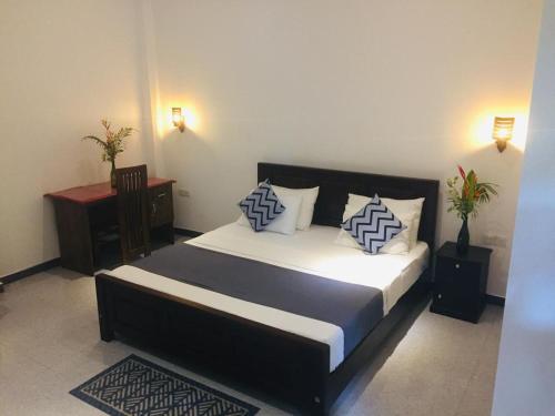 a bedroom with a large bed with blue and white pillows at Ceylon Avenue in Habaraduwa
