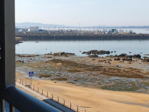 vistas a una playa con un muelle en el fondo en Mirador Mar de Castelao, 1ª línea de playa urbana, en Villanueva de Arosa