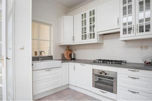 een witte keuken met witte kasten en een wastafel bij Een heerlijke woning op loopafstand van centrum! in Leeuwarden