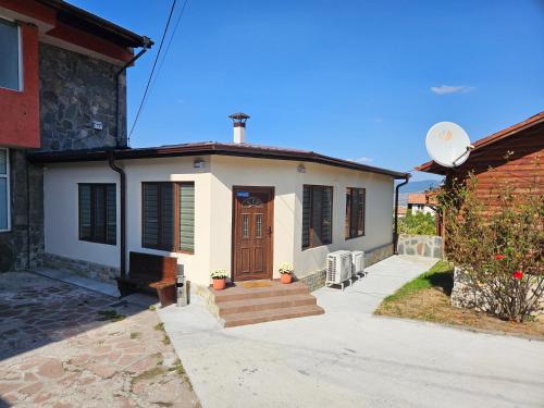 ein kleines weißes Haus mit einer Holztür in der Unterkunft Къща за гости Елит (Guest House Elite) in Saparewa Banja