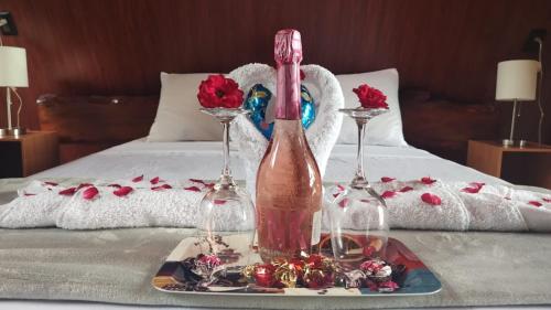a table with a bottle and two glasses on a bed at Yarumo Lodge, Río Celeste Black Chalets in Bijagua