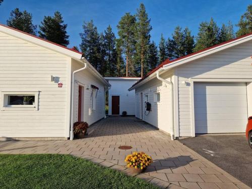 dos edificios blancos con dos puertas de garaje y flores en Övernattningsrum i separat gästhus på Sävastön en Boden