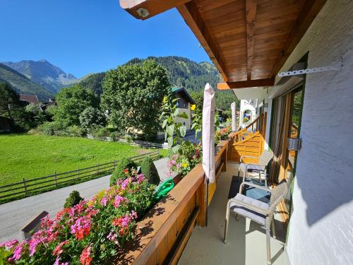 a porch of a house with chairs and flowers at am Mühlbach - Ferienwohnungen Luttinger in Bichlbach