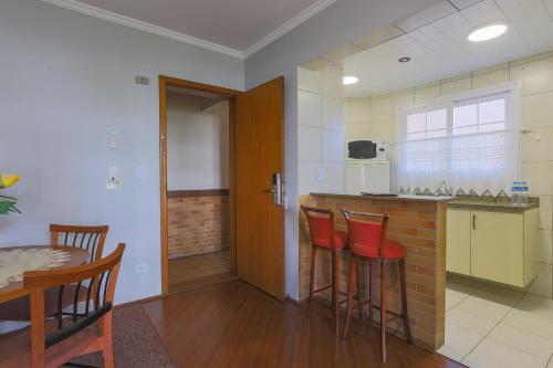 a kitchen with a table and some red bar stools at Hotel Palazzo Reale in Campos do Jordão
