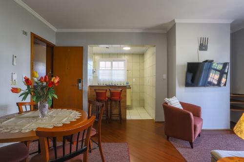 a living room with a table and chairs and a kitchen at Hotel Palazzo Reale in Campos do Jordão