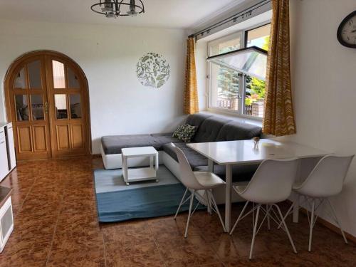 a living room with a couch and a table and chairs at Apartmán s terasou a zahradou na cyklostezce 