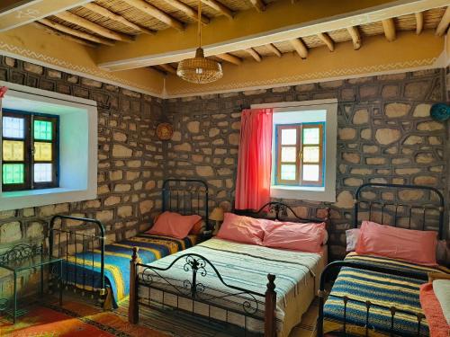 a bedroom with two beds in a stone wall at Kasbah Imini Restaurant & Hotel in Taourirt