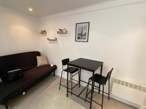 uma sala de estar com um sofá preto e uma mesa em Urban Chic Paris em Les Lilas