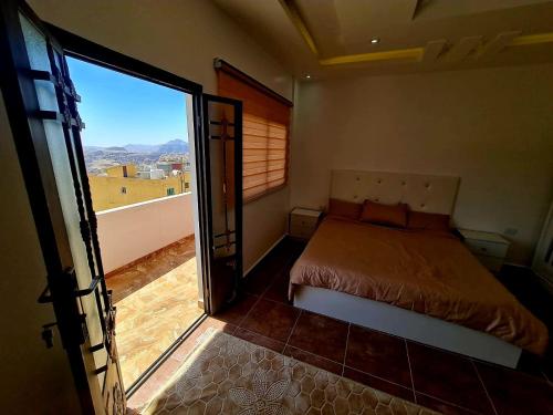 1 dormitorio con 1 cama y puerta corredera de cristal en Petra Sunset Bed & Breakfast en Wadi Musa