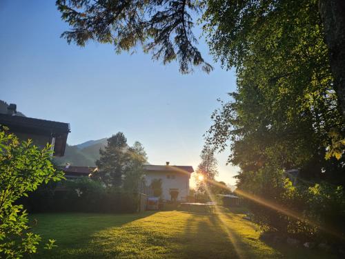 a house in the middle of a yard with the sun setting at am Mühlbach - Ferienwohnungen Luttinger in Bichlbach