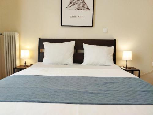 un grande letto con due cuscini e due lampade di 生活超便利的小公寓 ad Atene