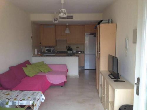 イスラ・クリスティナにあるcoqueto y acogedor apartamentoのリビングルーム(ピンクのソファ付)、キッチンが備わります。