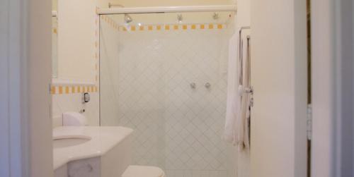 uma casa de banho branca com um chuveiro e um lavatório. em Vila Bueno Residence em Jaguariúna