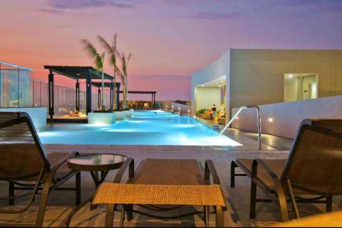 a swimming pool with tables and chairs in a house at Hermoso y lujoso piso 14 con Salida Directa a la playa y clubhouse increible in Santa Marta