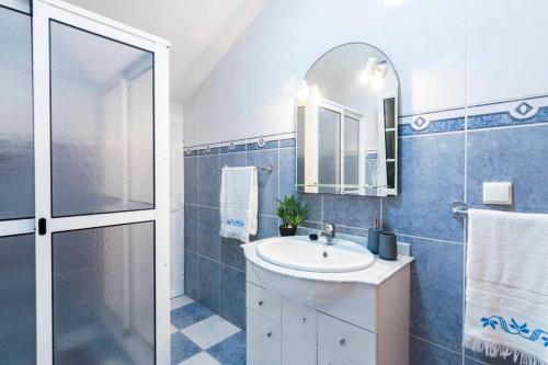 ein Bad mit einem Waschbecken, einer Dusche und einem Spiegel in der Unterkunft Branco's Apartment by GALMI in Ponta do Sol