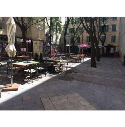 un patio extérieur avec tables, chaises et parasols dans l'établissement BudgetBnb 34, Toulon sympathique studio a 2 pas de l'opéra, à Toulon