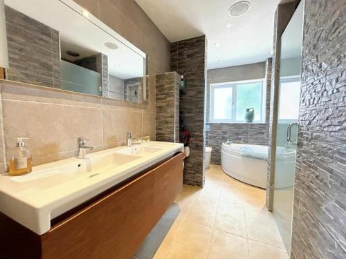 a bathroom with a sink and a tub and a mirror at 3 Chatsworth Road, Worsley in Manchester