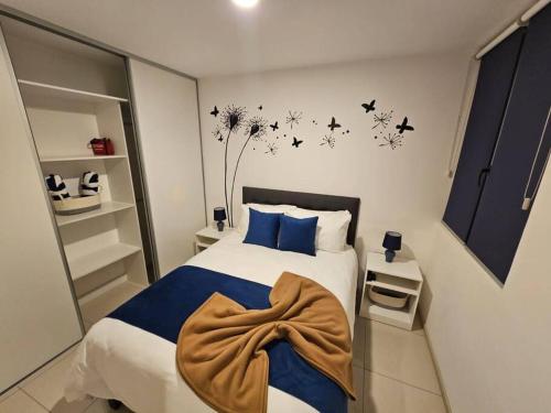 a bedroom with a bed with blue pillows and birds on the wall at Charming Retreat Heredia: Your Home Away from Home in Heredia