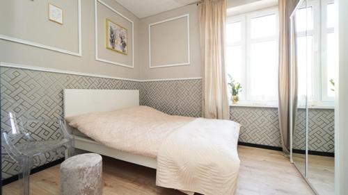 a bedroom with a white bed and a window at Przytulny elegancki APARTAMENT przy dworcu in Elblag