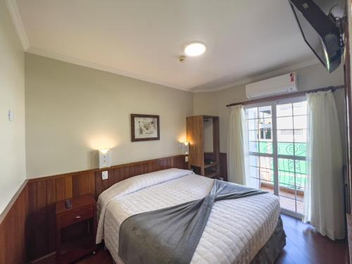 a bedroom with a bed and a large window at Hotel Palazzo Reale in Campos do Jordão