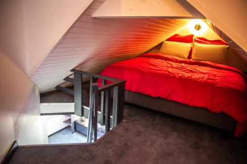 ein Schlafzimmer mit einem roten Bett im Dachgeschoss in der Unterkunft Bienvenue dans le violine 2 à 6 couchages in Cholonge