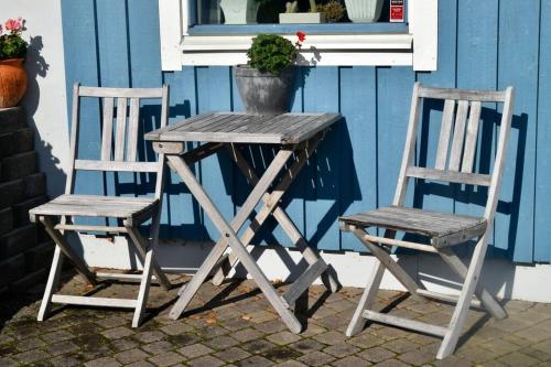 2 sillas y mesa de madera con maceta en Sjöstuga/gästhus i skärgården., en Åkersberga