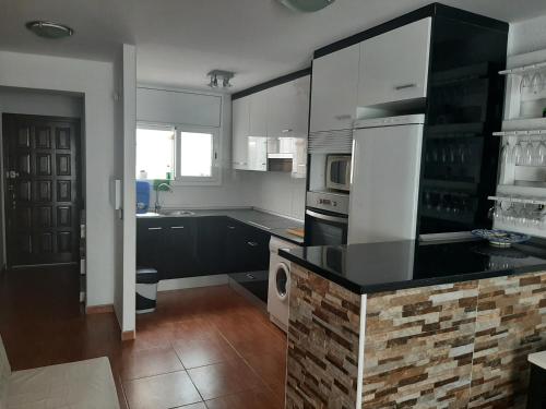 a kitchen with white cabinets and a black counter top at Casa Miami Platja in Miami Platja