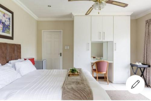 a bedroom with a large white bed with a ceiling fan at Jewel of Jozi in Edenvale
