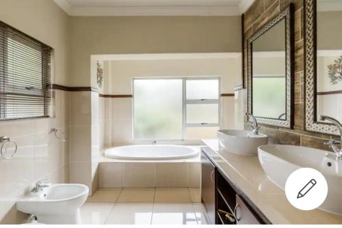 a bathroom with two sinks and a tub and a toilet at Jewel of Jozi in Edenvale