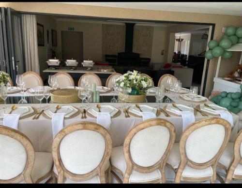 a long table with chairs and a table with white table cloth at Jewel of Jozi in Edenvale