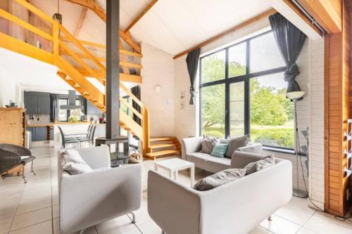 a living room with white furniture and large windows at Superbe et chaleureux gîte familial in Beauraing