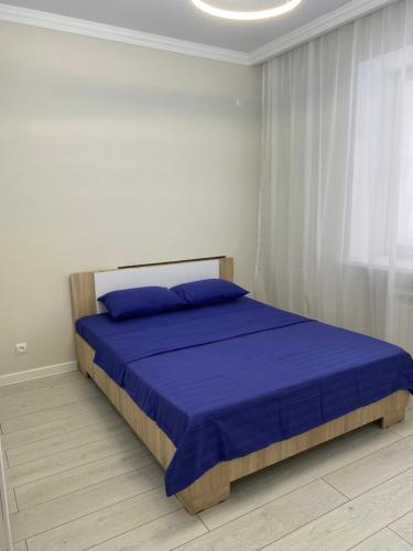- une chambre avec un lit doté de draps bleus et une fenêtre dans l'établissement 2х комнатная квартира в элитном ЖК Альтаир в центре города, à Aqtöbe