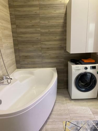 a white tub in a bathroom with a washing machine at 2х комнатная квартира в элитном ЖК Альтаир в центре города in Aktobe