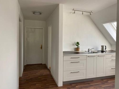 a white kitchen with a sink and a window at Renovated apartment near nature in Birkerød