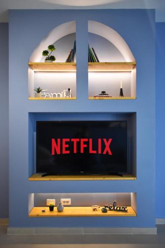 una TV a muro con il cartello Netflix sopra di Vibrant Apartment a Tirana