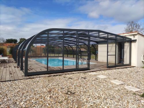 a pool house with a metal frame around a swimming pool at Maison avec piscine privée, proche plage in Avrillé