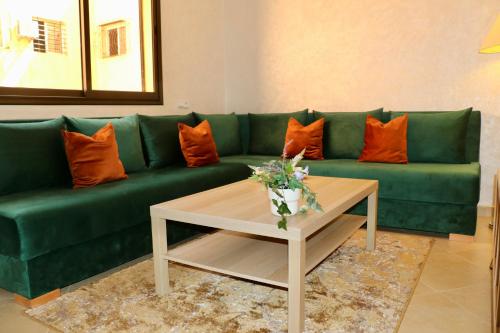 um sofá verde com almofadas laranja numa sala de estar em Magnifique Appartement Marrakech - 2 Chambre 2 Salle de Bains em Marrakech