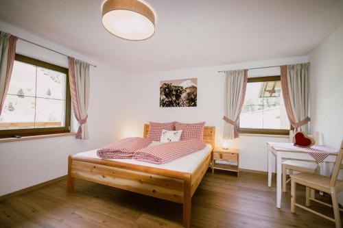 a bedroom with a bed and a table and windows at Nedererhof - Zimmer Enzian mit Gemeinschaftsküche in Schmirn