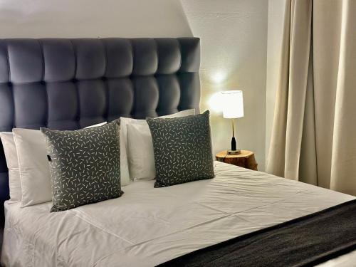 a bed with a blue headboard and two pillows at Rosetta Fields Country Lodge in Henburg Park