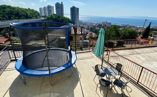 een blauwe trampoline op een balkon met een tafel en stoelen bij Apartman Luna *** in Rijeka