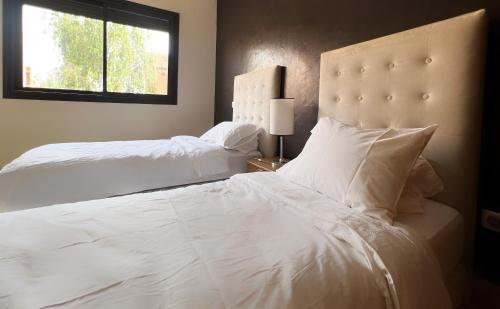 1 Schlafzimmer mit 2 weißen Betten und einem Fenster in der Unterkunft Luminous apartment with pool view in Marrakesch