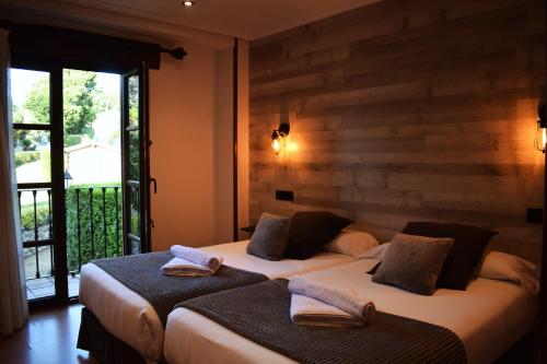 two beds in a room with a window at Hotel Spa San Marcos in Santillana del Mar