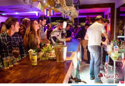 a group of people standing at a bar at Marco Polo Party Hostel in St Julian's